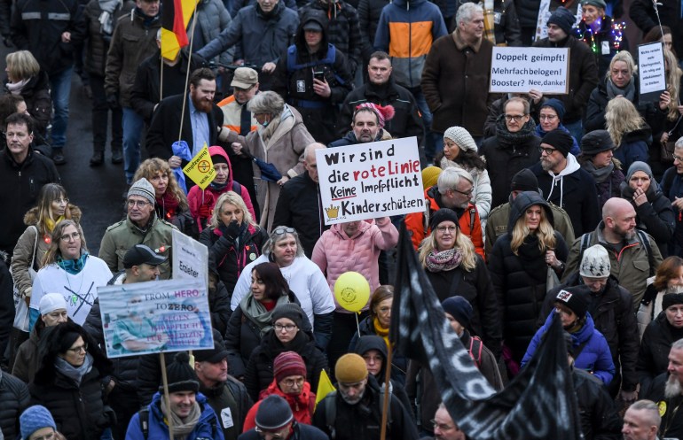 Protesters take part at a demonstration and hold banners reading "We are the red line, no compulsory vaccination, protect the children" and "Double vaccinated, lied to multiple times! Booster? No thanks" in Duesseldorf, western Germany,