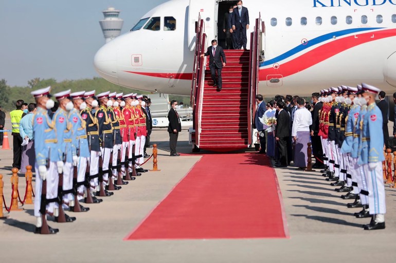 Hun Sen walks down the steps of his plane on the tarmac of the Naypyidaw airport to a red carpet and an honour guard of soldiers dressed in pale blue tops and white trousers