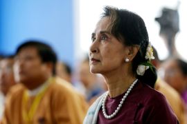 Myanmar's Aiung San Suu Kyi in a tradiitonal outfit and wearing a string of pearls listens at an event in Yangon in 2019