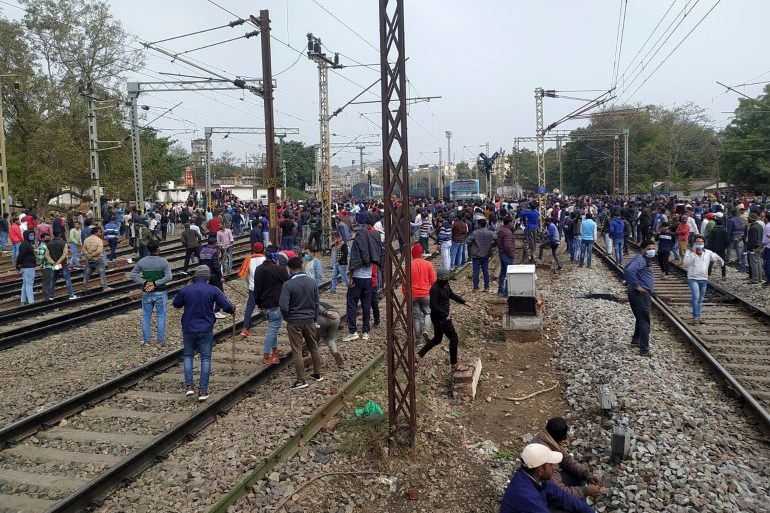 People gather near a train set on fire by angry mobs in Bihar