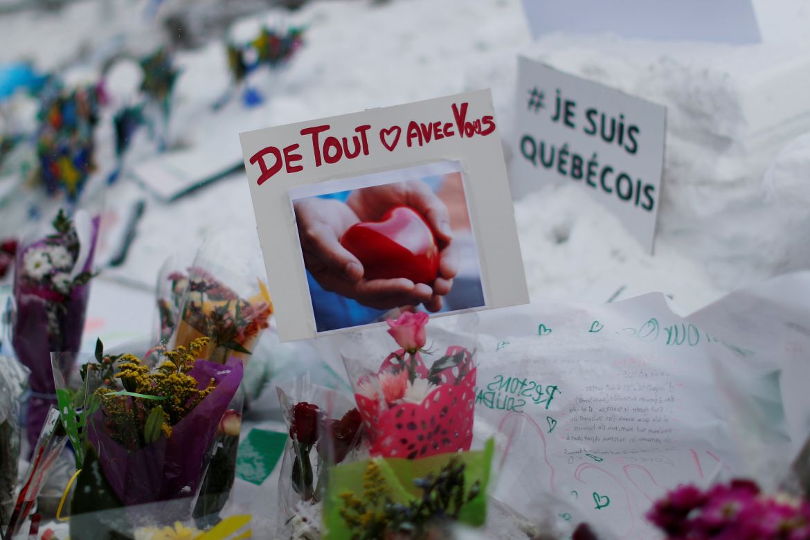 A sign reads 'With you with all our heart' at a memorial to the victims