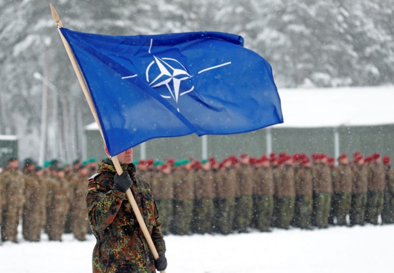 A soldier carries the NATO flag during German Minister of Defence Ursula von der Leyen's visit to German troops