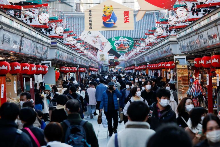 Visitors wearing protective face masks walk under decorations for the New Year at Nakamise street leading to Senso-ji temple at Asakusa district amid the COVID-19 pandemic, in Tokyo
