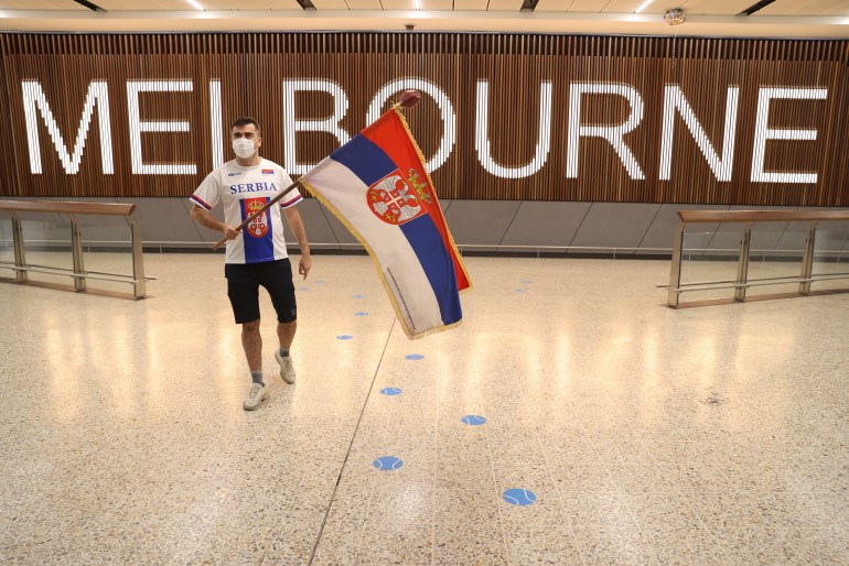 A man with a Serbian flag waits to greet the men's number one tennis player Novak Djokovic at the arrivals hall of Melbourne international airport