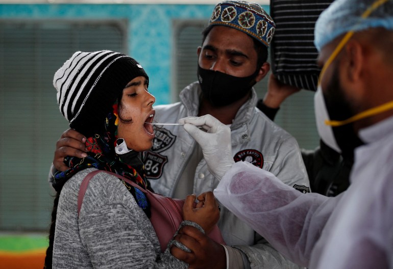 A health worker collects a swab sample from a woman in Mumbai