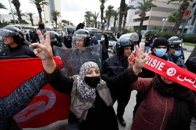 A woman holds her hands up in front of a police line in Tunis