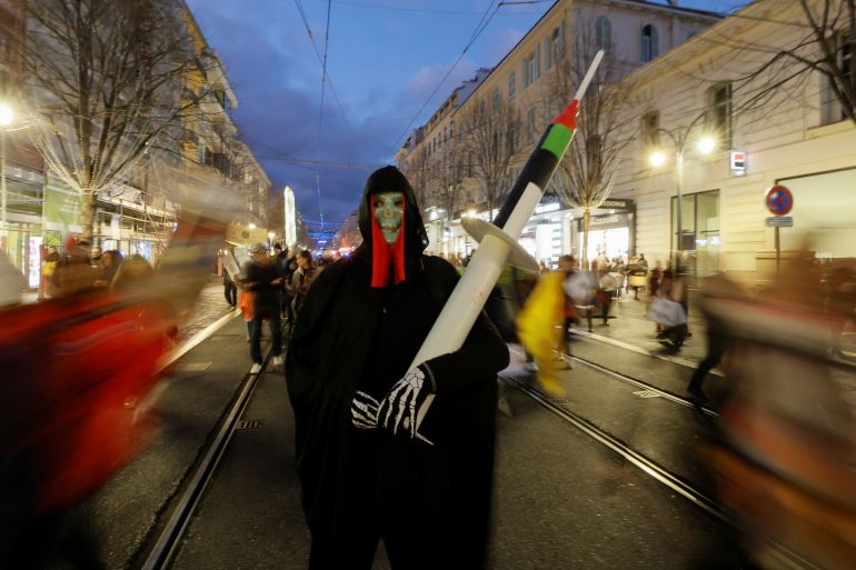 A man wearing a death mask, holds a mock-up syringe during a demonstration to protest against a bill that would transform France's current coronavirus disease (COVID-19) health pass into a "vaccine pass", in Nice, France