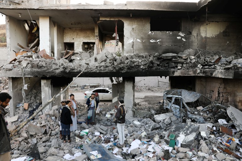 Guards stand on the rubble of a house hit by Saudi-led air strikes in Sanaa