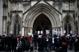 Protesters hold signs outside the Royal Courts of Justice in London