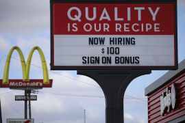 A 'Now Hiring' sign outside a Wendy's fast food restaurant with the worlds "Now Hiring $100 sign on bonus"