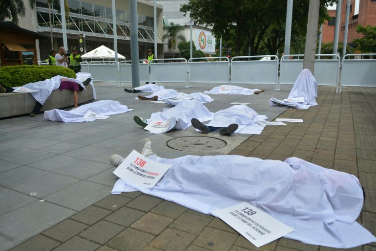 Activists lie covered with sheets to represent corpses outside the venue of the 49th OAS General Assembly, to protest against the killing of social and youth leaders, in Medellin, Colombia
