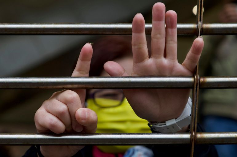 A supporter gestures with their hands to signify the "Five demands - not one less", outside a court in Hong Kong