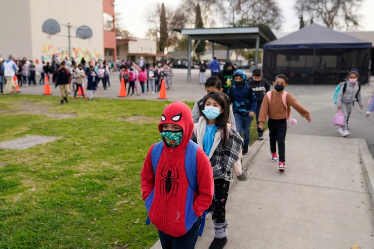 Masked Children walk towards school building