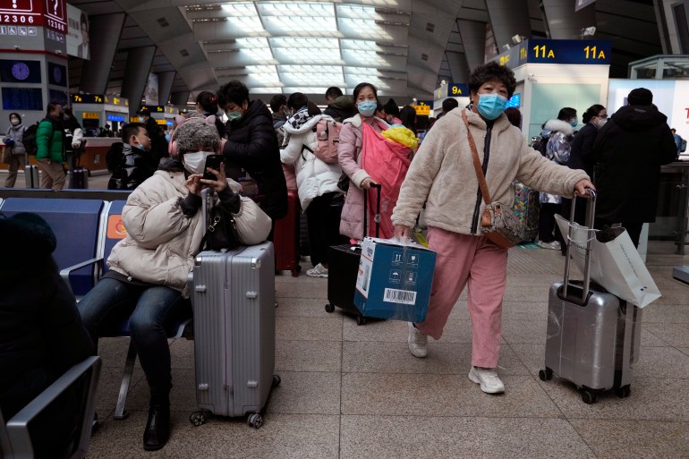 Passengers wearing masks to protect from the coronavirus wait for their train at the South Train Station in Beijing, China