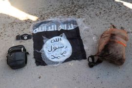Flag and bags of Islamic State group fighters who were arrested by the Kurdish-led Syrian Democratic Forces after they attacked Gweiran Prison
