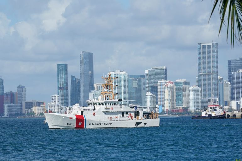 A US Coast Guard ship sails in the sea off Miami with skyscrapers in the background