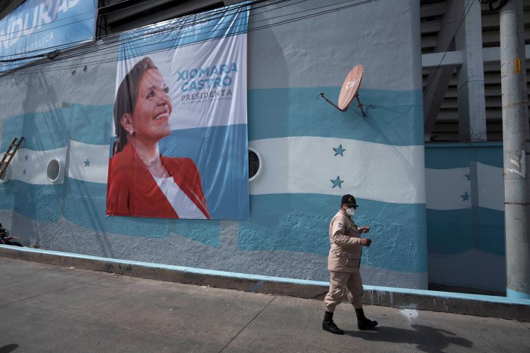 Man walking past banner of Xiomara Castro