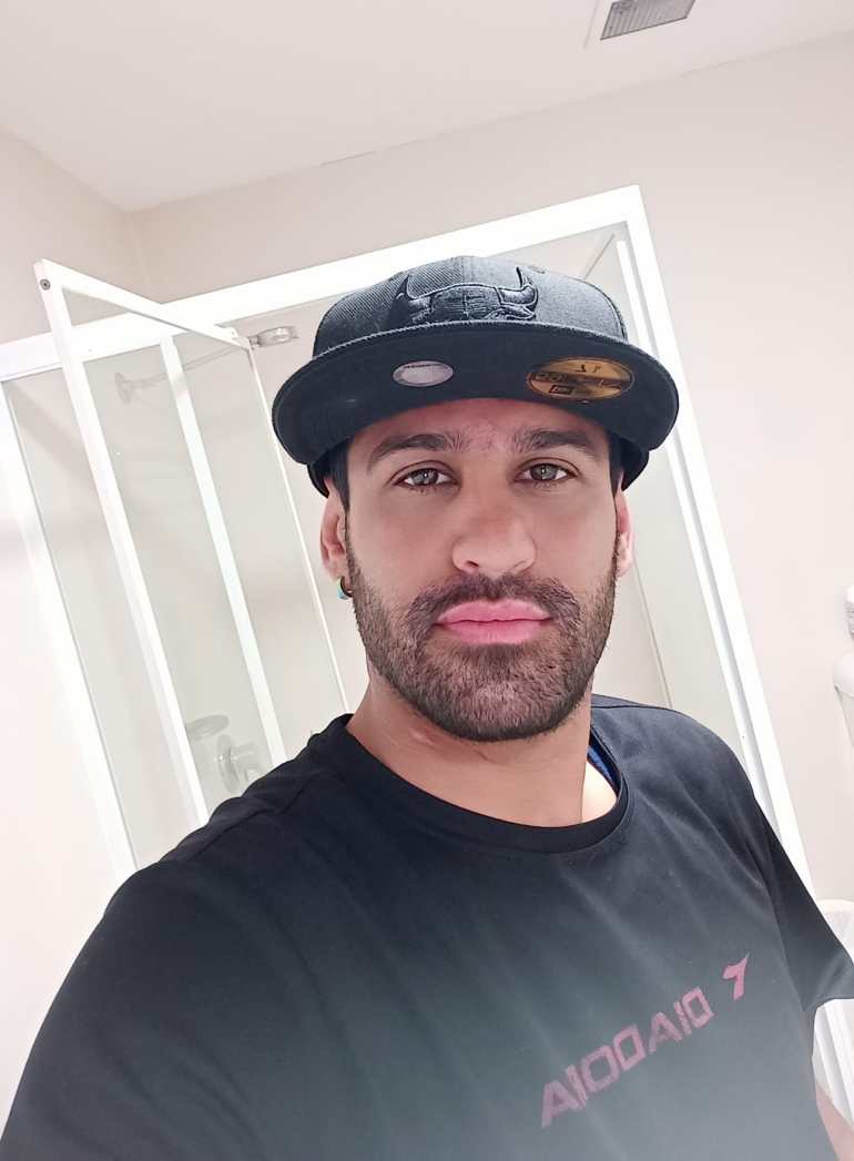 A selfie of a bearded Amin Afravi wearing a black t-shirt and black cap. 