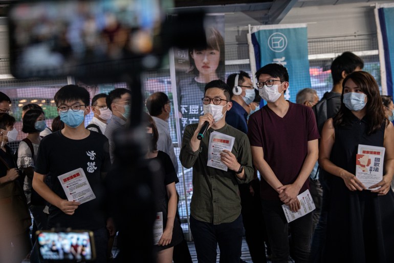 Pro-democracy activists and Demosisto members Joshua Wong (L), Jannelle Leung (2-L), Nathan Law (C), Sunny Cheung (2-R), and Gwyneth Ho (R), all wearing face masks, distribute flyers against China's controversial national security law for Hong Kong