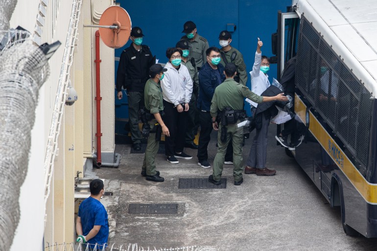 Pro-democracy activists and politicians brought out in handcuffs to get into a prison van to be taken to a pre-trial hearing. 