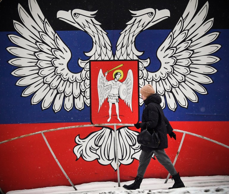 In this file photo taken on January 19, 2022, a pedestrian walks past a huge state emblem of the self-proclaimed Donetsk People's Republic in Donetsk, eastern Ukraine