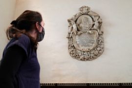 A woman looks at a memorial to Tobias Rustat
