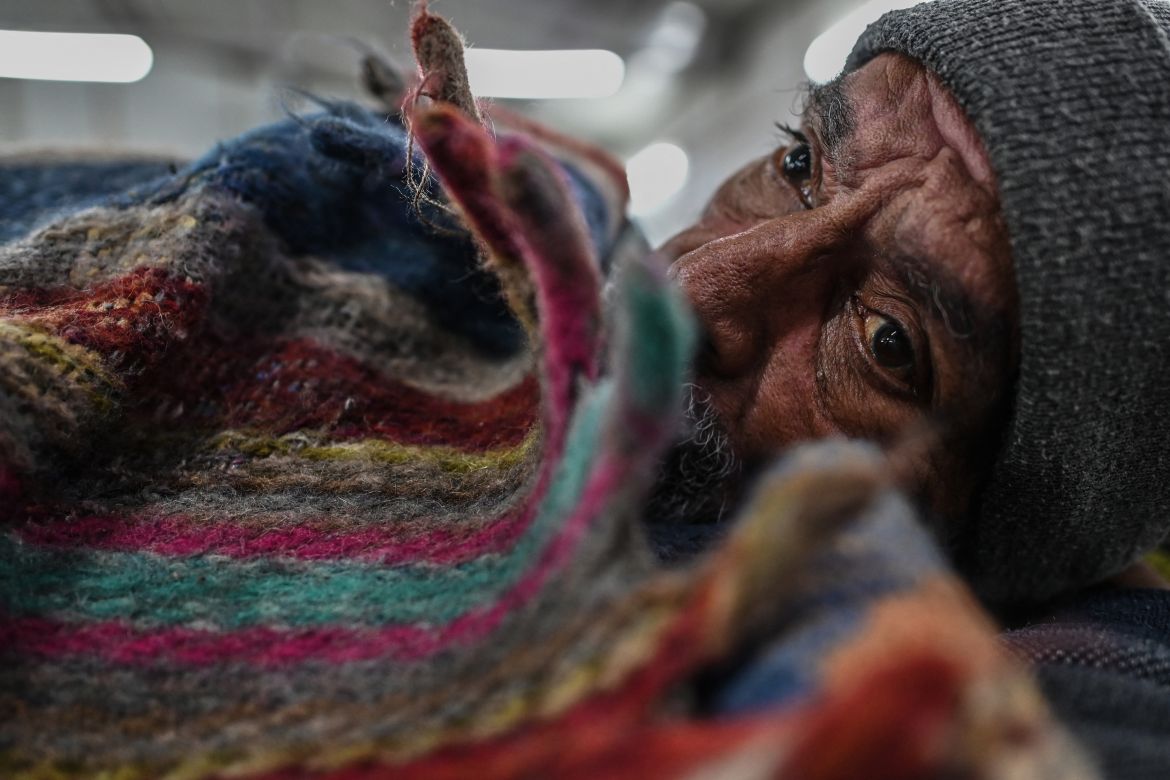 In this picture taken on January 29, 2022, shows a homeless man wrapped in a quilt sitting inside a government-run shelter in New Delhi.