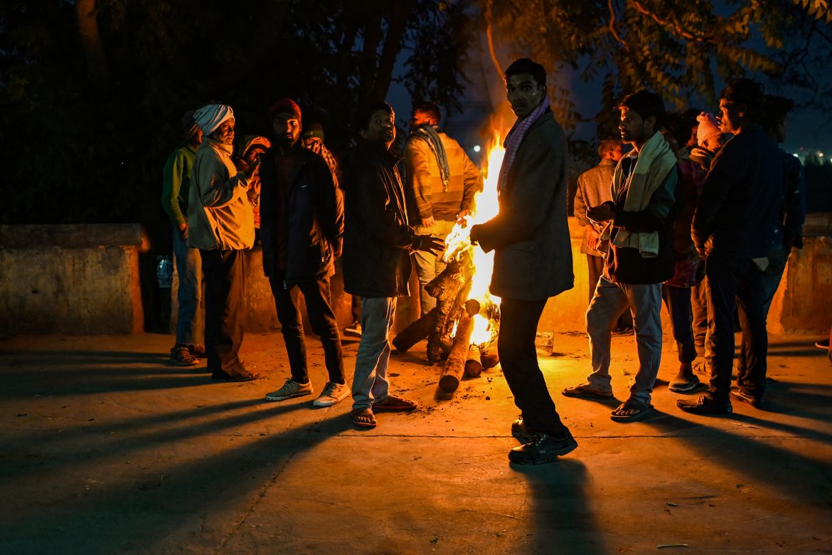 In this picture taken on January 29, 2022, shows homeless people gathered besides a bonfire to keep themselves warm in a wintry evening in New Delhi.