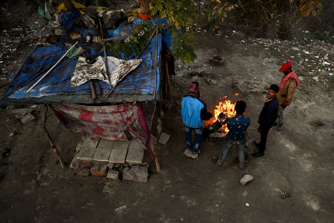 In this picture taken on January 29, 2022, shows homeless people gathered besides a bonfire to keep themselves warm in a wintry evening outside a government-run shelter in New Delhi.
