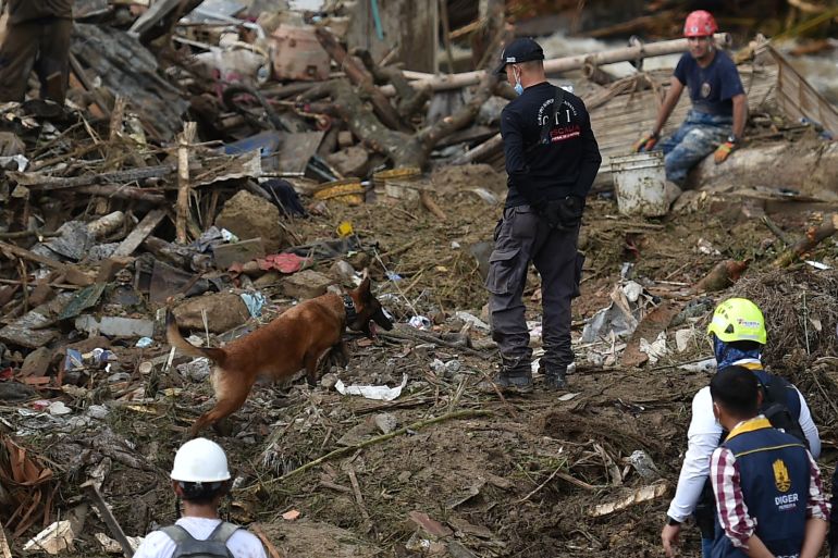 A rescuer and his dog search for survivors in a pile of mud and debris after the landslide in