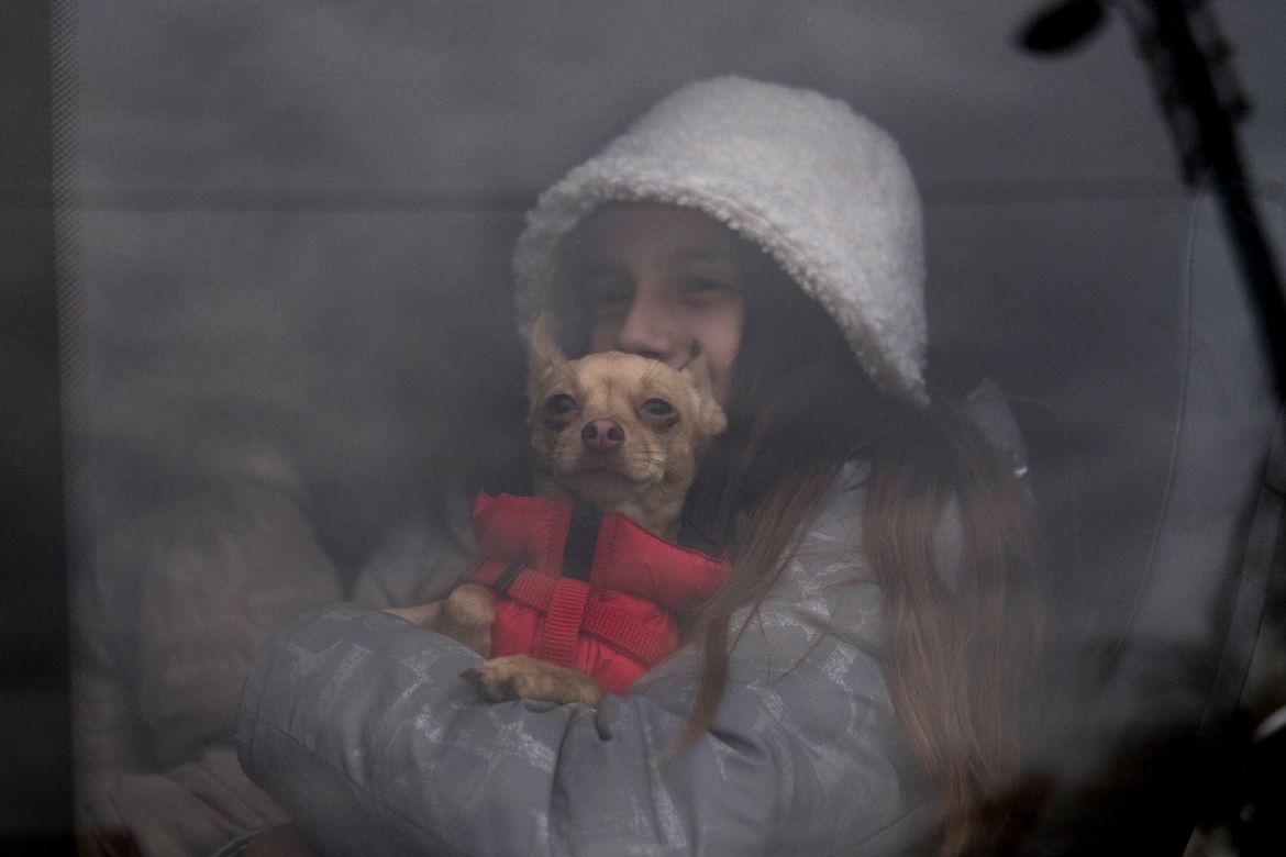A girl holding her dog waits together with her family for the departure of a bus that takes refugees to towns nearby Siret.