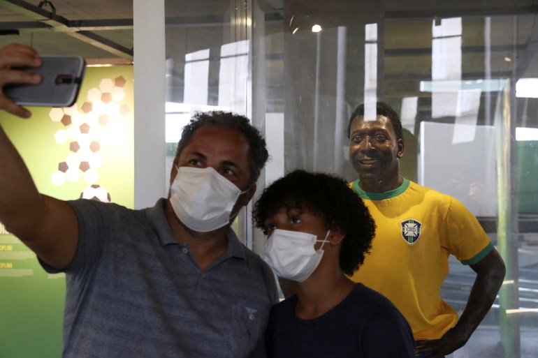 People take a photo with a statue of Pele