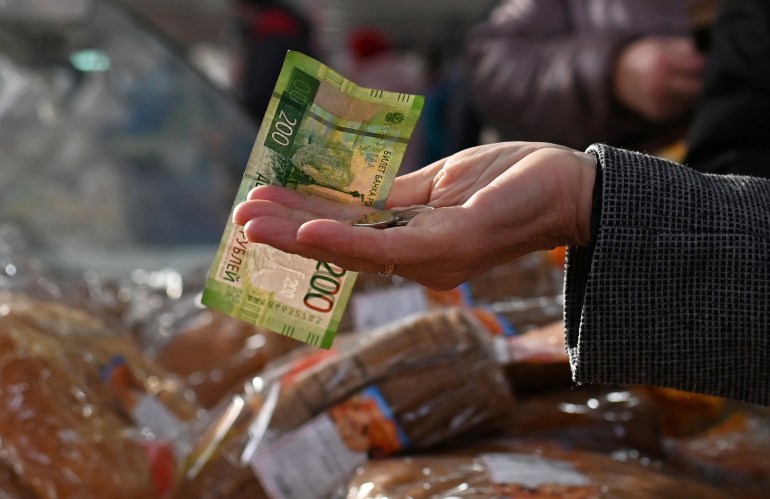A customer hands over Russian rouble banknotes and coins to a vendor at a market in Omsk, Russia