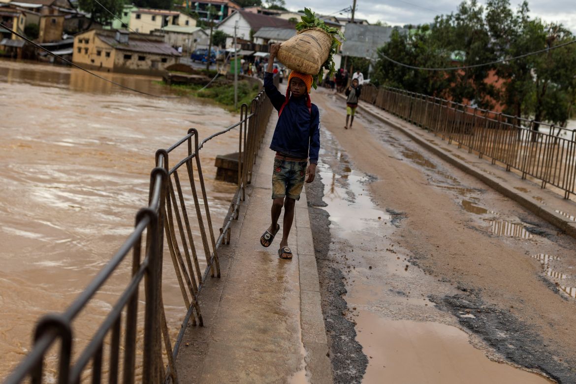 A boy carries vegetables in a flooded area, as Cyclone Batsirai sweeps inland, in Fianarantsoa