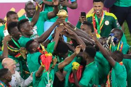 senegal players crowd together to hold aloft the AFCON trophy after their win over Egypt