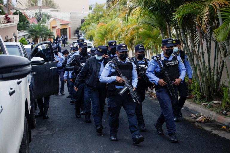 Police officers surround the house of former Honduran President Hernandez
