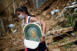 A woman carries a picture at the site of a mudslide in Brazil