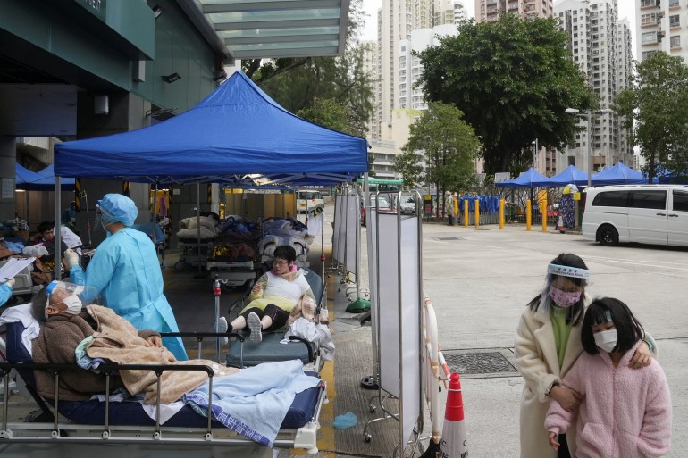 Patients beneath canopies lie in beds and sit in wheelchairs in a makeshift treatment area outside a Hong Kong hospital