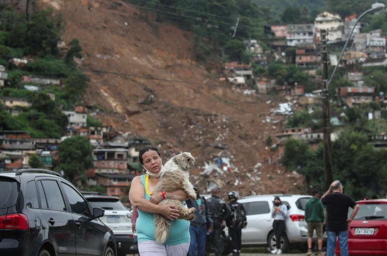 A woman carries her dog at a shelter for people displaced by landslides in Brazil