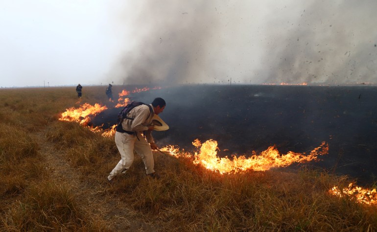 People work to extinguish the fire that continues to consume trees and pastures in San Luis del Palmar, province of Corrientes, Argentina.