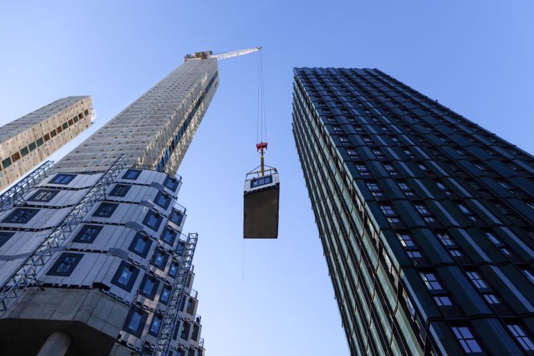 A crane lifts a section of apartment to be fitted into position at a construction site in Croydon, Greater London, U.K.