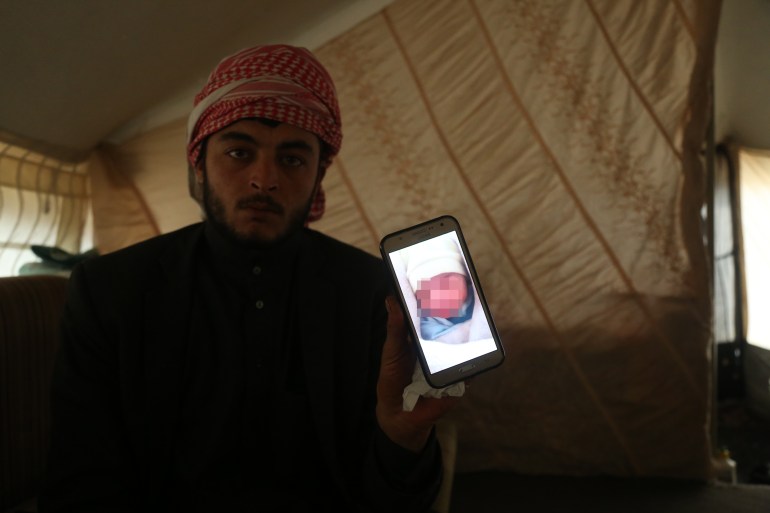 Mohamad Al-Hassan with a photo of his daughter Fatima bundled in blankets while she was still alive