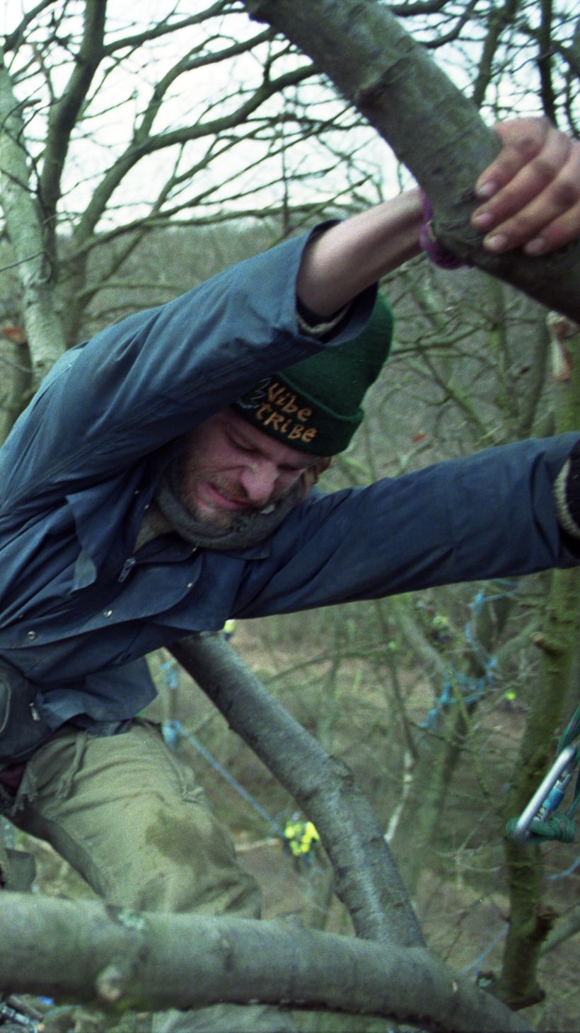 A white male protestor is pulled from a tree by climbers in Newbury, the UK