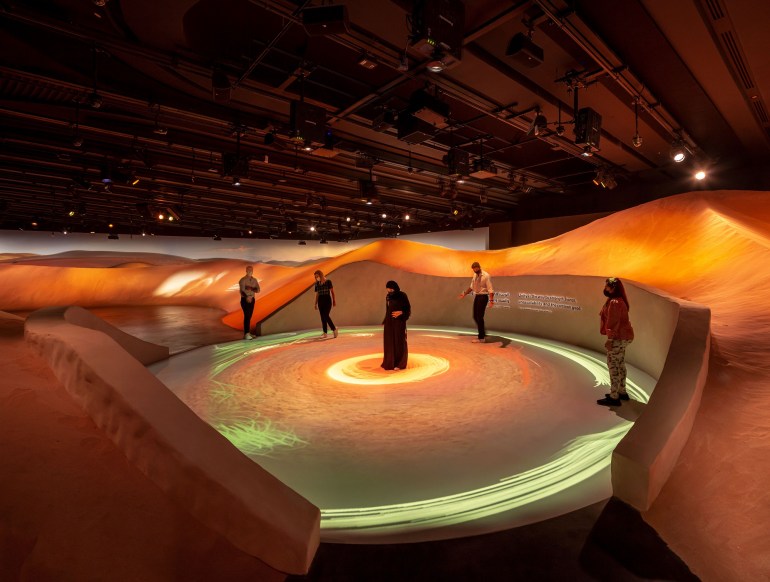 Guests stand in a circular red and orange coloured section of the UAE pavillion which xplains the country's founding
