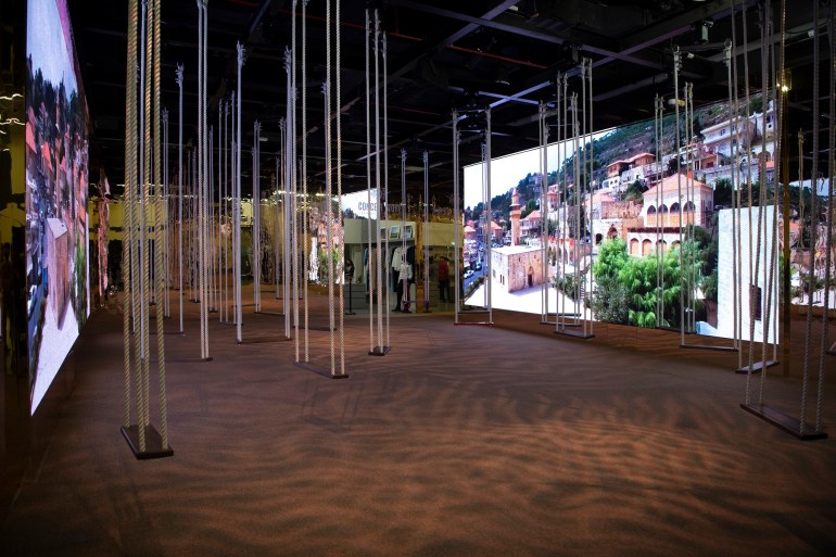 An installation with many swings is seen at the Lebanon Pavilion with a photo of Lebanon displayed on a large screen