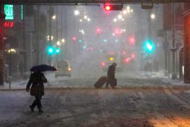 Pedestrians navigate Chicago's famed Loop in windy, falling snow and slushy street conditions.
