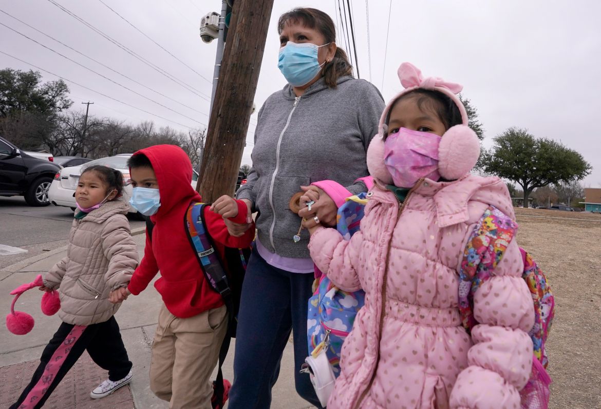 With winter weather coming, an adult helps school children cross the street in Dallas