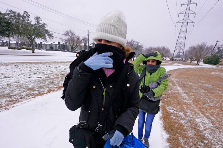 Amanda, left, and Rebecka try to keep warm as they walk to work during a light freezing rain in Dallas, Texas.