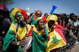 Senegalese soccer fans celebrate as they await the return of their national football team in Dakar