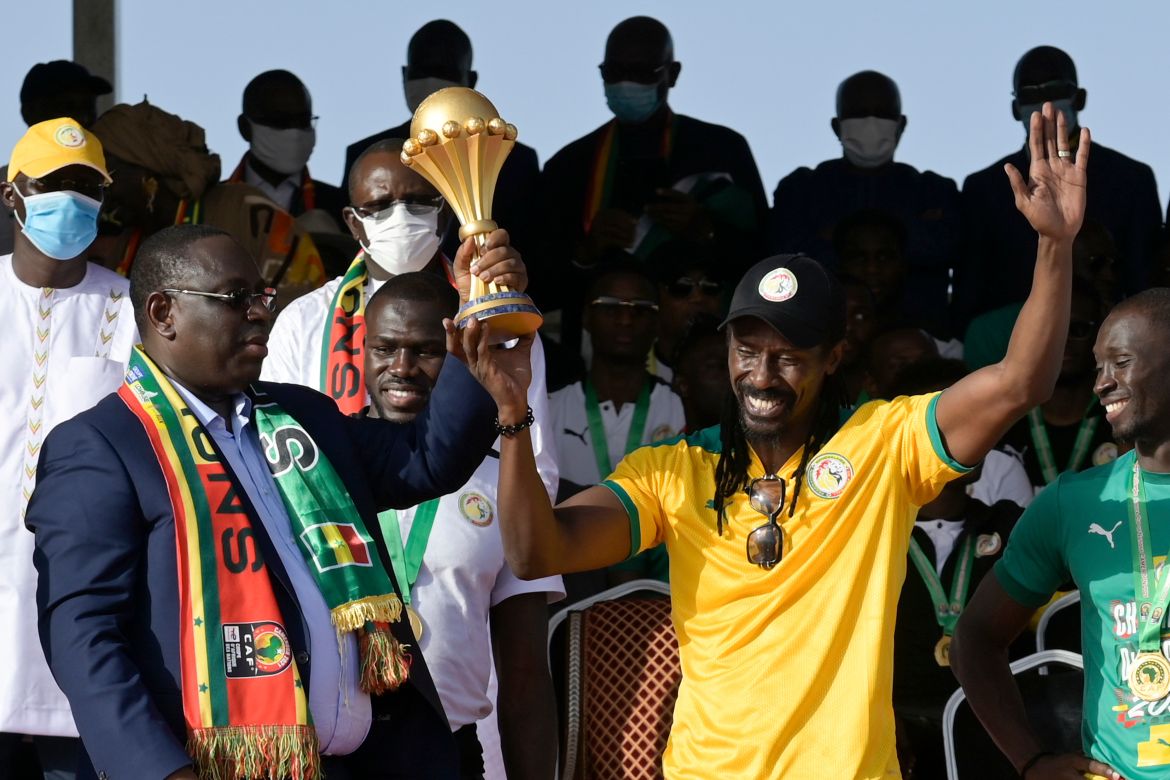 Senegal's President Macky Sall and coach Aliou Cisse hold the AFCON trophy during a ceremony at the Dakar airport after the national football team's return
